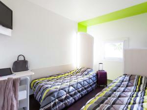 a bedroom with two beds and a desk and a window at Hotel F1 Vesoul - En cours de rénovation in Vesoul