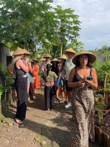 a group of people wearing straw hats walking down a path at Daphne Homestay & Cooking Class in Senggigi