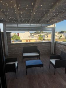 a room with chairs and tables and a large window at Illumina House 3 in Giurdignano