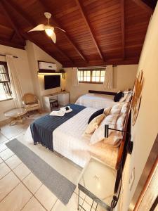 a bedroom with a large bed and a tv at Hotel Pousada da Lagoa - Casa Californiana in Garopaba