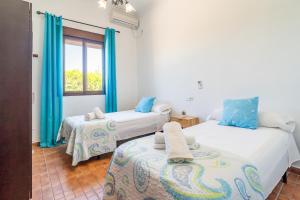 a bedroom with two beds and a window with blue curtains at Casa Rural Villa Lucrecia in La Lantejuela +40 photos