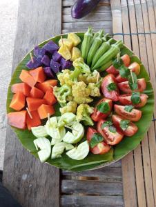 a plate of vegetables and fruit on a wooden table at Daphne Homestay & Cooking Class in Senggigi