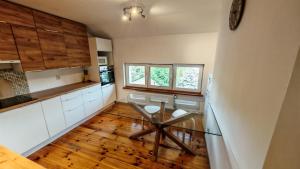 a kitchen with a glass table and wooden floors at Willa 2 piętro in Szczecinek