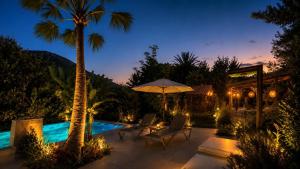 a pool with two palm trees and an umbrella at A historic STONE VILLA with private garden, terrace and private pool just for you in Kyrenia