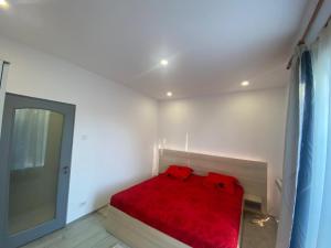 a bedroom with a red bed with a red blanket at Apartament Kiri in Mangalia
