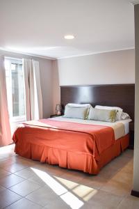 a bedroom with a large bed with an orange blanket at Demetrio Hotel Apart in Olavarría +117 photos