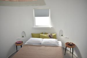 a bedroom with a bed with a window and two tables at Thronos in Vlychada