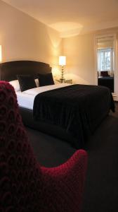 a bedroom with a large bed and a chair at Hotel am Doktorplatz in Rheda-Wiedenbrück