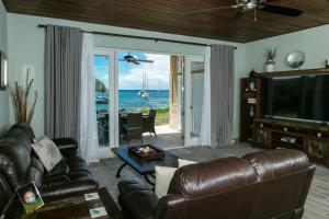 a living room with a leather couch and a television at Mahalo Villa Beachfront Generator in Cruz Bay