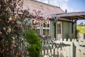 a green house with a white fence at Penbontbren Luxury Bed and Breakfast in Aberporth