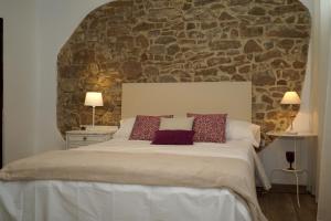 1 dormitorio con 1 cama grande y pared de piedra en Casa El Carolino, en Larraga