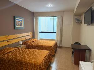 a hotel room with two beds and a television at Hotel El Brujo Centro Histórico in Trujillo