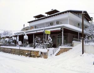 a house covered in snow in front at O Fotis Studios & Apartments in Ioannina