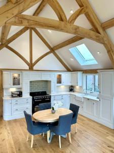 a kitchen with a wooden table and blue chairs at Holly Barn in Worcester +16 photos