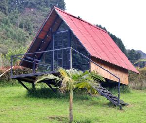 a small building with a red roof and a palm tree at Hotel Rancho Olimpo in Sesquilé