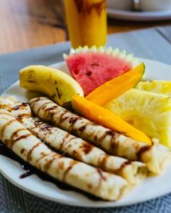 a plate with three sausages and fruit on a table at Jaje Paje Villa in Paje