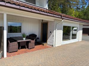 a patio with a table and chairs in front of a house at Leilighet på RyenToppen med gapahuk in Kristiansand