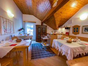 a dining room with two tables and a kitchen at B&B Casa Riz in Castello di Fiemme