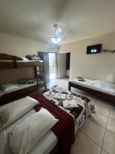 a room with three beds and a ceiling fan at Pousada Natalino Broleze in Águas de Lindoia