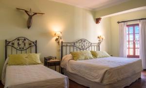 a bedroom with two beds and a cross on the wall at Hotel Asturias in Cafayate