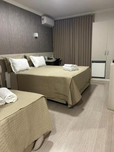 a hotel room with two beds and a table at Realce Hotel in Jaú +86 photos