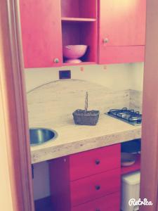 a kitchen counter with a sink and red cabinets at Il Nido Salentino in Martano