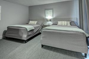 a bedroom with two beds and a chair at Motel Express in Saint-Antonin