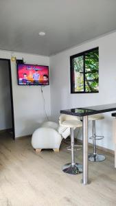 a room with a table and stools and a tv at Cabaña el Pilar in Fusagasuga
