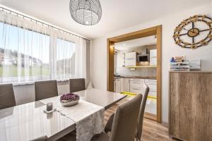 a dining room with a table and chairs and a kitchen at Apartmán Zara in Telgárt