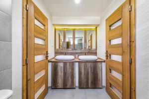 two sinks in a bathroom with wooden doors at Apartmán Zara in Telgárt +12 photos
