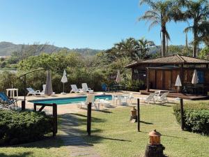 a swimming pool with chairs and a house at Hotel Pousada da Lagoa - Casa Californiana in Garopaba
