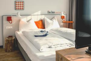 1 cama blanca grande con sábanas blancas y almohadas de color naranja en I´m Inn Wieselburg en Wieselburg