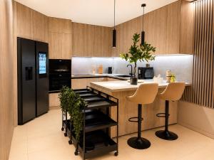a kitchen with a black refrigerator and a counter with stools at Vila GARUFA Wellness & Spa in Vysoké Tatry +51 photos