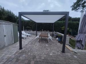 a pavilion with a table and chairs on a patio at La cabane des fées in Yvoir