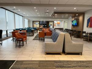 a restaurant with couches and tables and chairs at Holiday Inn Express Big Rapids by IHG in Big Rapids