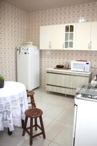 a kitchen with a table and a white refrigerator at Casa Alceste - Casa inteira, com garagem privativa, a 10 minutos a pé do Centro Histórico de Diamantina - 05 hóspedes in Diamantina