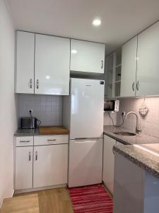 a kitchen with white cabinets and a white refrigerator at Namaste in Sesimbra +4 photos