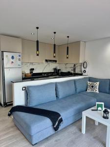 a living room with a blue couch and a kitchen at KAZA Aouchtame 2 in Laʼzîb