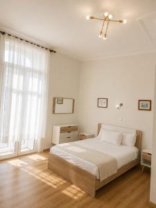 a white bedroom with a bed and a large window at Central Guest House in Figueira da Foz