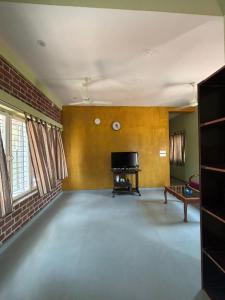 an empty living room with a television and a piano at The Luxora Villa in Kuilapayam