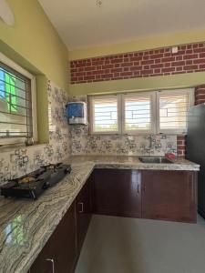 a kitchen with a counter and a sink and windows at The Luxora Villa in Kuilapayam