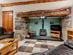 a living room with a stone fireplace and a tv at 3 Bed in Bala oc-52810 in Llanuwchllyn