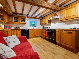 a kitchen with wooden cabinets and a red couch at 3 Bed in Bala oc-52810 in Llanuwchllyn