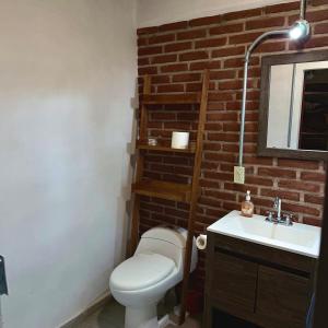 a bathroom with a toilet and a sink and a brick wall at Loft acogedor cerca de Jardines de México in Vidalrstn +3 photos