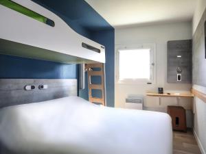 a bedroom with a white bed and a blue wall at Hotel Ibis Budget Abbeville in Abbeville +37 photos