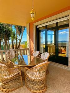 a glass table and chairs on a porch with a view of the ocean at La Pepa Sanxenxo in Sanxenxo