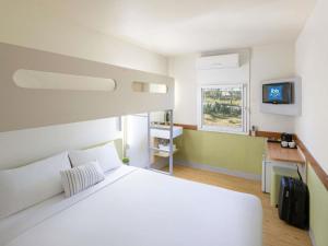 a bedroom with a large white bed and a window at ibis Budget - Newcastle in Newcastle