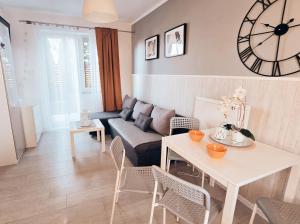 a living room with a table and a clock on the wall at Apartamenty Perła Bałtyku in Władysławowo