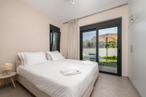 a bedroom with a white bed and a large window at Luxe benedenwoning Nula Kos in Kos