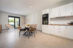 a kitchen with white cabinets and a table and chairs at Luxe benedenwoning Nula Kos in Kos